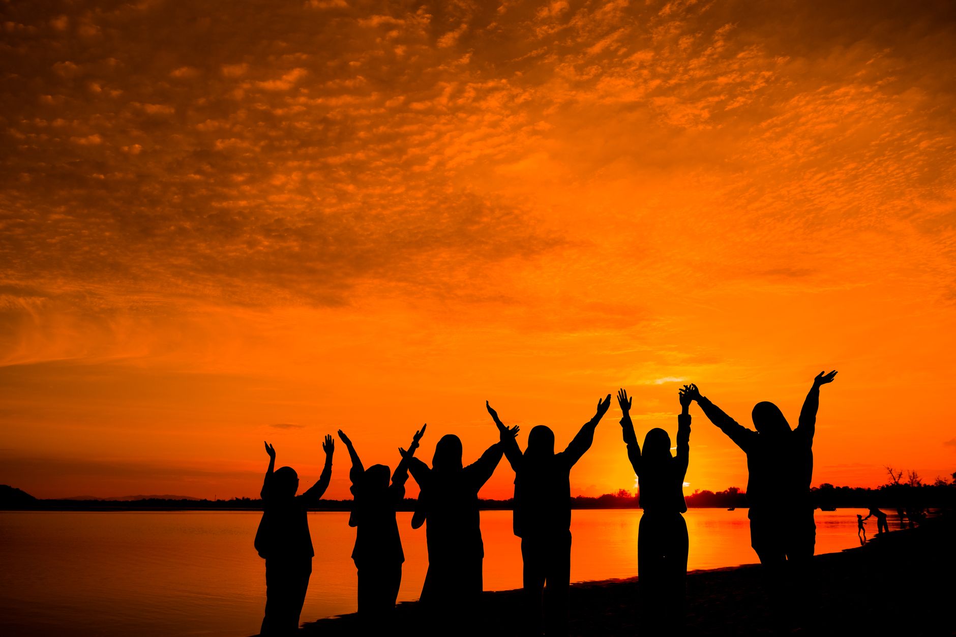 group of friends on lakeshore at sunset