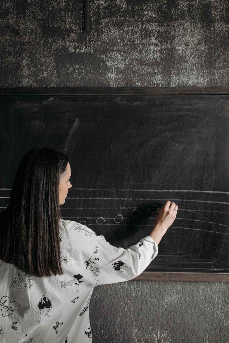 woman wearing sweater writing on a blackboard