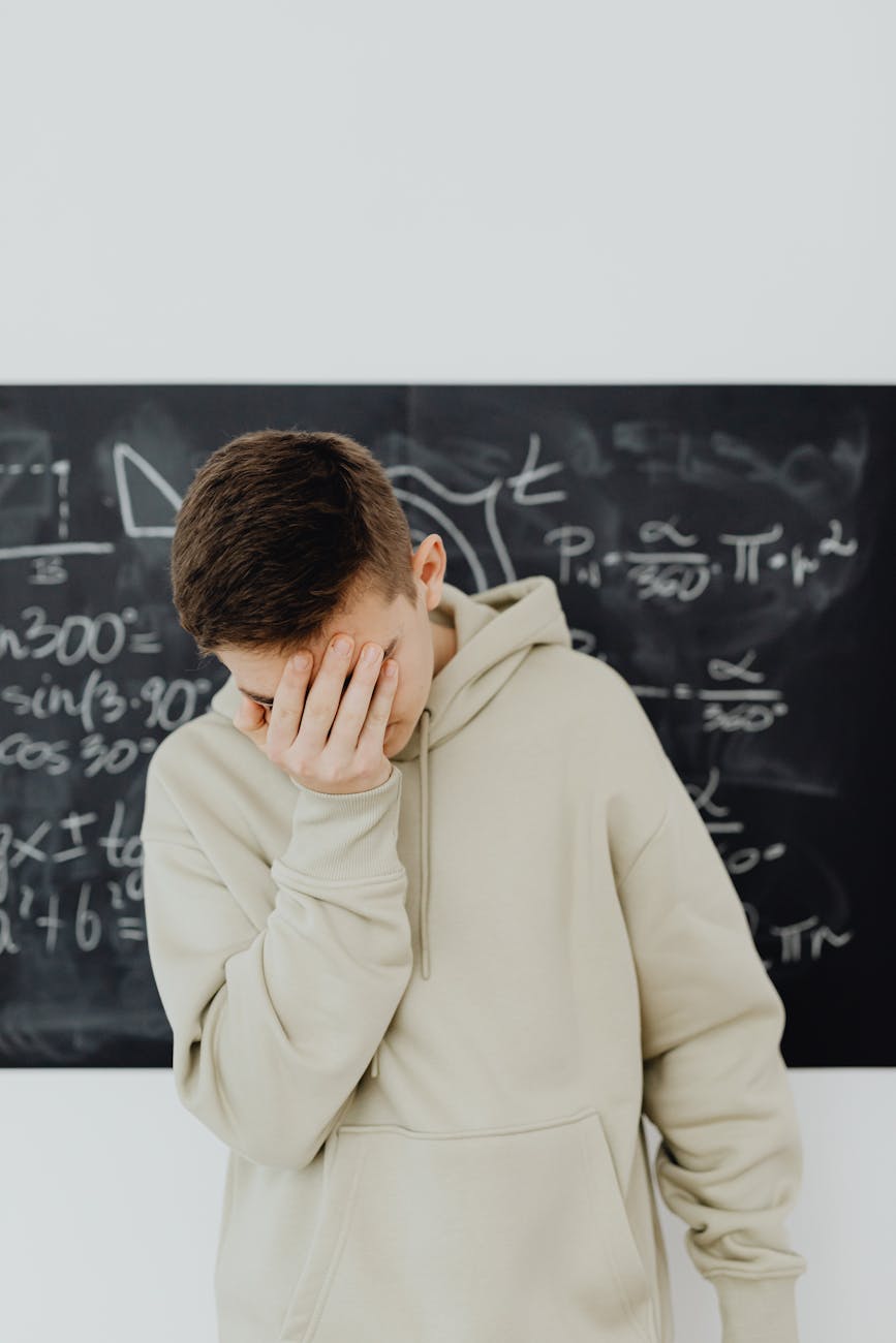 resigned young man in front of blackboard with trigonometry calculations
