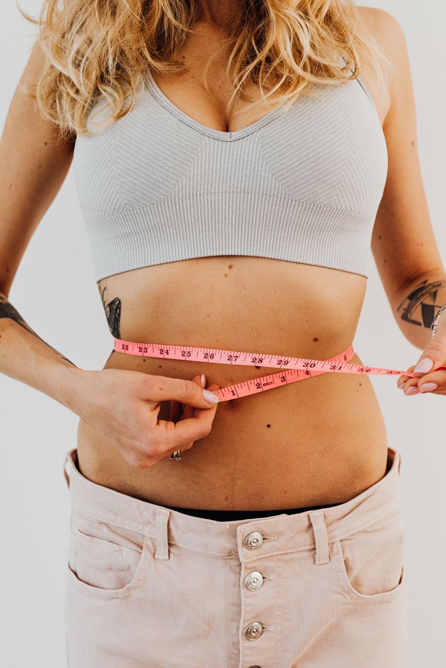 woman in sports bra holding a tape measure on her waist